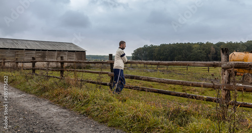 Young caucasian man standing on stackade farm in rural czech landscape © Space Creator