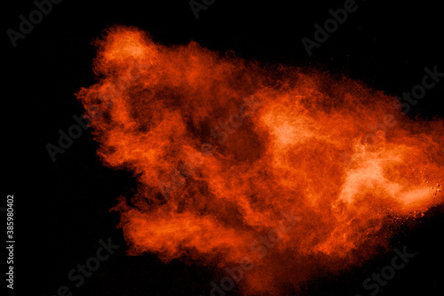 Abstract explosion of orange dust on black background.Freeze motion of orange powder burst.