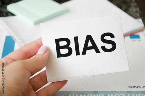 The word bias is written in a notebook held by a businesswoman. judgment bias concept. photo