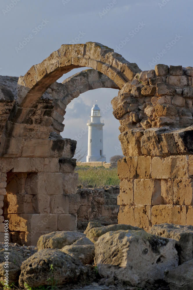 View of the lighthouse through the arch of the Saranta Kolones Castle. Ruined medieval fortress inside the Paphos Archaeological Park on the island of Cyprus