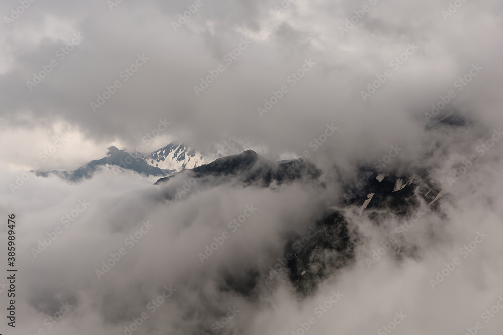 Clouds and fog in the Alps, the highest mountains in Europe. Austria or Italy in autumn, bad weather and rocks in cold windy day