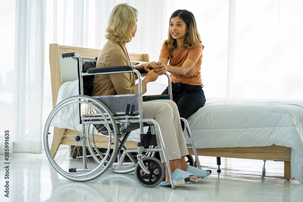 caucasian senior patient recover woman on wheelchair and mixed race daughter in hospital room new normal. caucasian senior patient recover woman on wheelchair and mixed race daughter in hospital room new normal.