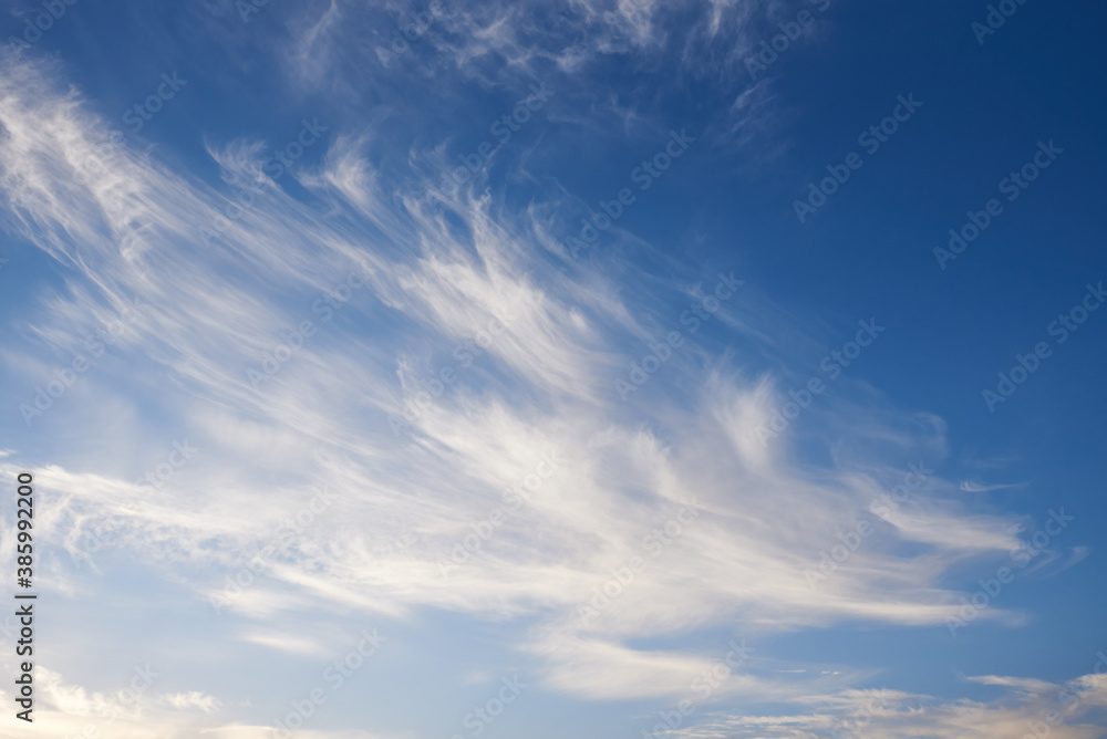 Flying white clouds and blue sky in sunlight.