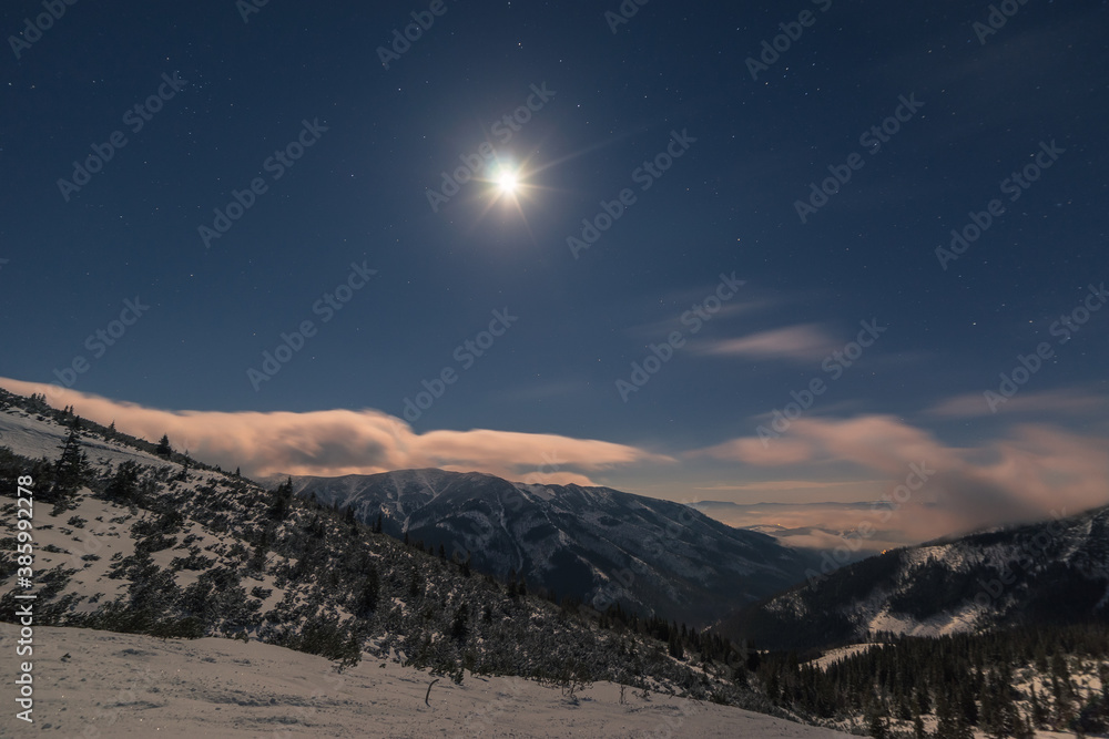 the moon shines on the snowy landscape of the mountains and clouds fly on the horizon the moon shines on the snowy landscape of the mountains and clouds fly on the horizon