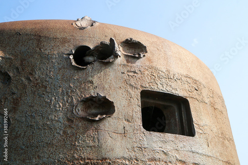 The bullet holes in the armor of the bunker turret from second world war.  photo