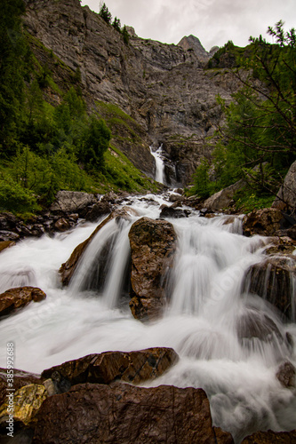 Small waterfalls streaming in green forest in long exposure. water in motion - swiss Alps