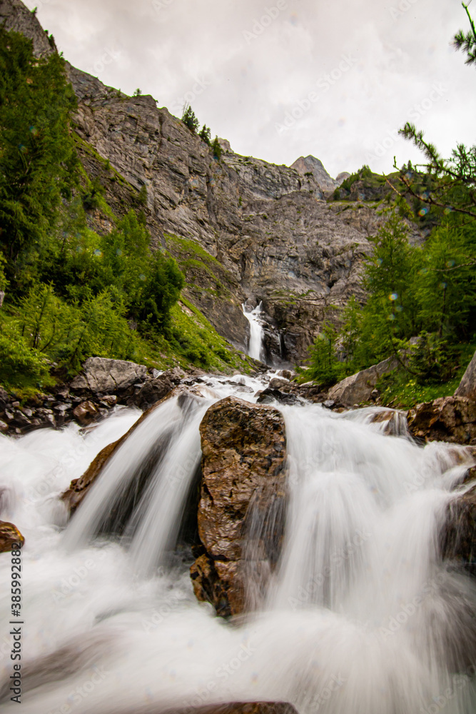 Small waterfalls streaming in green forest in long exposure. water in motion - swiss Alps Small waterfalls streaming in green forest in long exposure. water in motion - swiss Alps