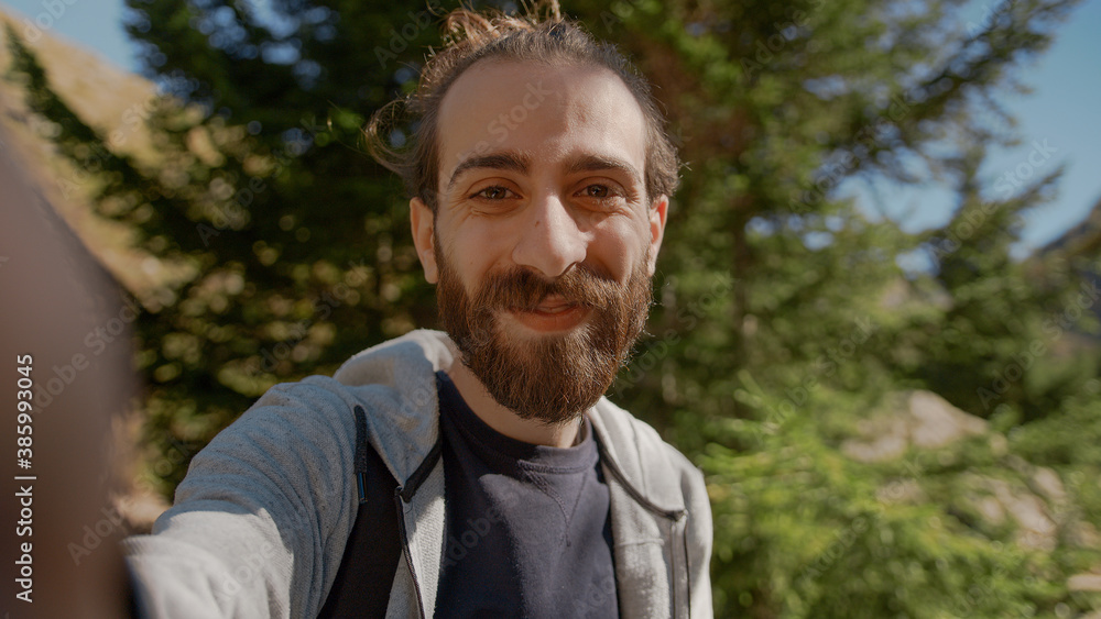 Hippie climber with his backpack behind him, with his handheld camera or phone, salutes the audience or the person he is talking, vlogger or video chat in nature concept Hippie climber with his backpack behind him, with his handheld camera or phone, salutes the audience or the person he is talking, vlogger or video chat in nature concept