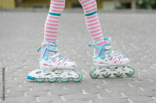 The child learns to roller skate. Girl in pink tights. Childhood and hobby concept