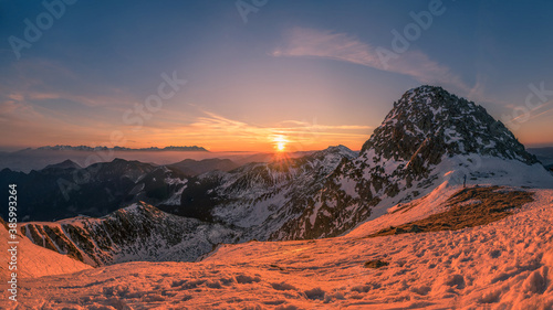 Sunrise in high mountain environment with snow and soft clouds in the sky