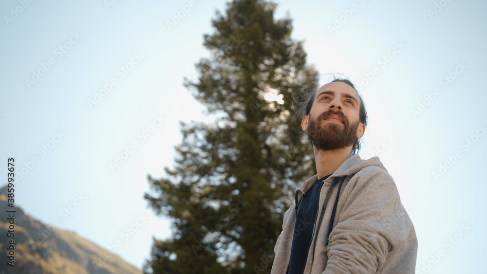 Young hipster male looking away and smiles, background tree forest and nature concept Young hipster male looking away and smiles, background tree forest and nature concept