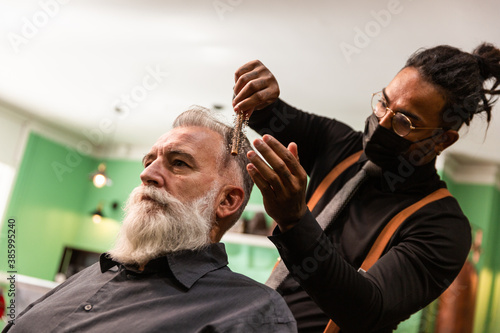 african american barber with mask coronavirus pandemic prevention comb white caucasian male with white beard