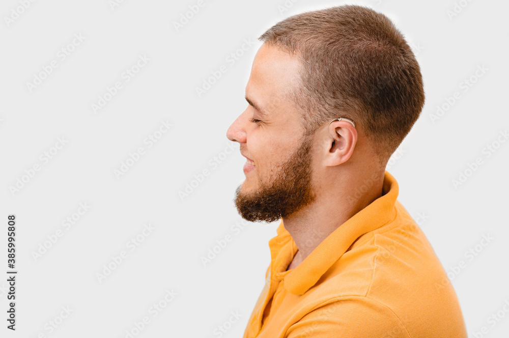Smiling man wearing in latest generation hearing aid behind the ear. Hearing solution for adult people with deafness. Isolated on white background Smiling man wearing in latest generation hearing aid behind the ear. Hearing solution for adult people with deafness. Isolated on white background