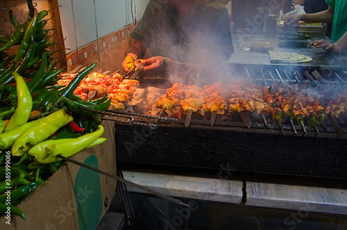 Grilled kebab Turkish street food. chicken wings on the street. Chicken wings roasting on the grill in cafe on the street. Green chili pepper on the foreground. Focus on meat. Istanbul, Turkey.