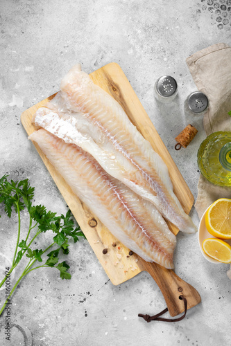Cod fillet. Raw cod fillet on a chopping Board on a light gray kitchen table. Preparation for cooking fish. Top view