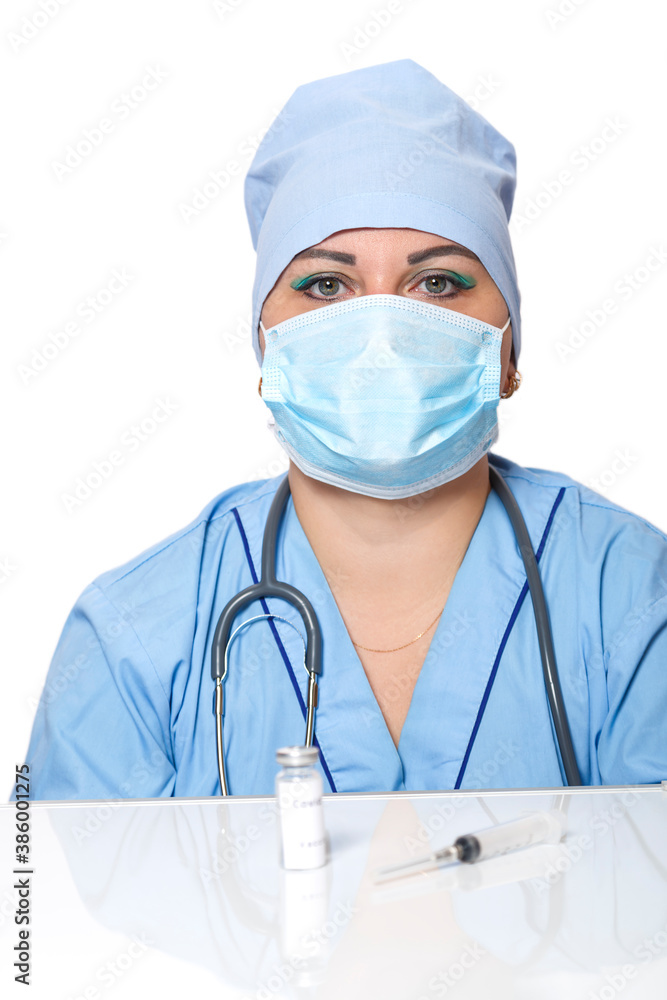 On the table lies a virus prevention vaccine and a syringe in the background a doctor in a mask. On the table lies a virus prevention vaccine and a syringe in the background a doctor in a mask.