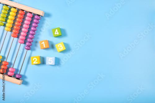 Flat lay, Top view of wooden bricks and abacus toy background with copy space for text, Numeral cubes with numbers 1 to 5 and colorful abacus,  Math concept photo