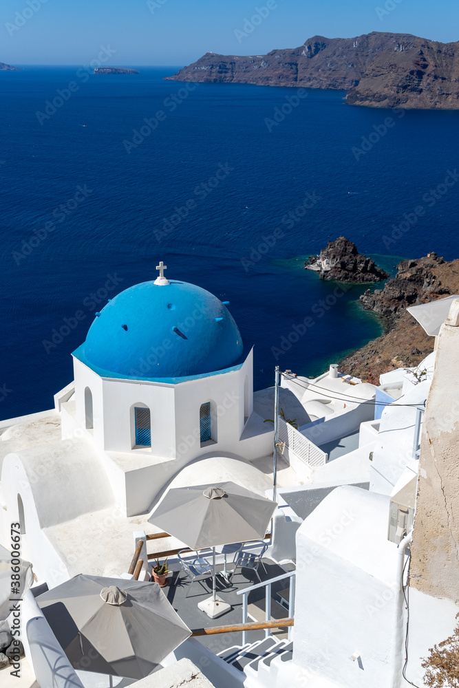Beautiful view of Oia town in Santorini island with old whitewashed houses and typical blue domes of orthodox churches, Greece. Greek landscape on a sunny day