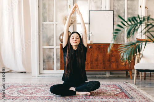 Beautiful brunette fitness woman meditate, doing yoga indoors at home. Staying fit and healthy photo