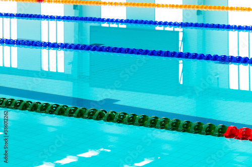 Track & lanes of a competition swimming pool..Indoor swimming pool with empty lanes..Olympic standard swimming pool &  diving pool, water and lines ,