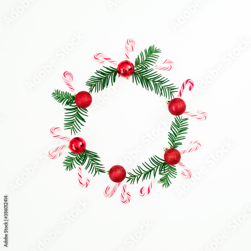 Christmas frame made of evergreen branches and red balls decoration on white background. Festive background