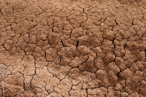 The natural backdrop of red, cracked, dry earth. Clay barren dry land close-up. A lifeless desert on earth.