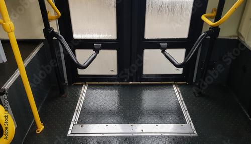 Bus door with yellow handles, interior view. The mechanism for opening and closing the doors of modern public transport in the city.