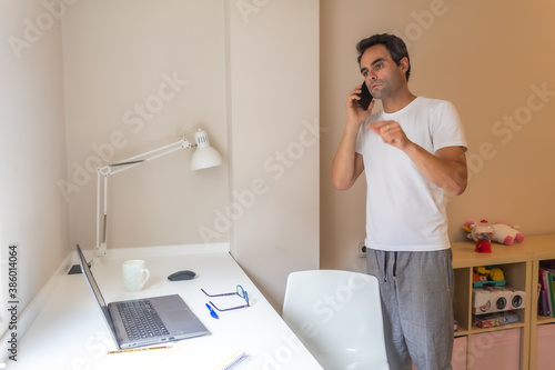 businessman standing with his mobile phone working at home in home clothes while answering messages