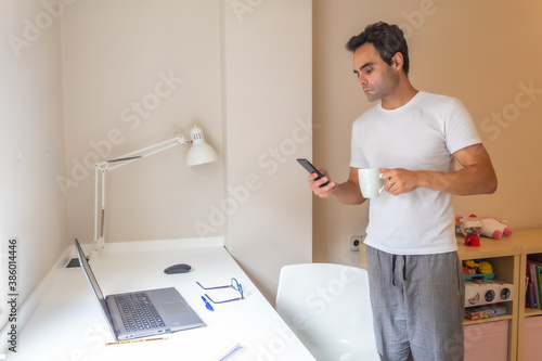 businessman standing with his mobile phone working at home in home clothes while answering messages