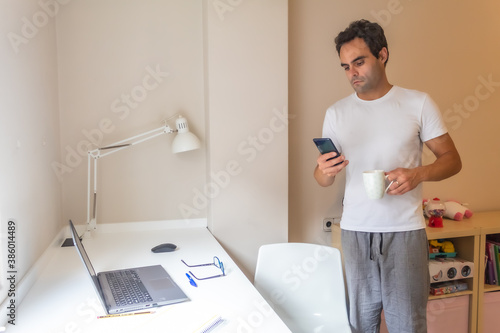 businessman standing with his mobile phone working at home in home clothes while answering messages