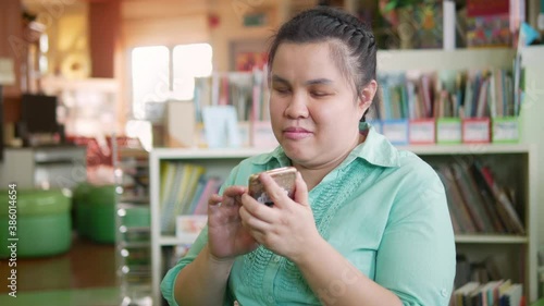 Portrait of Asian young blind person woman enjoy using smart phone with voice accessibility for persons with disabilities in creative workplace..