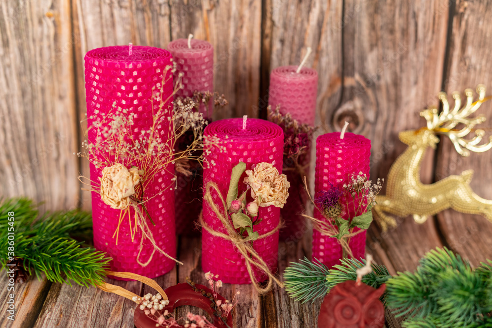 Handmade pink honey candles made of natural wax on a background of wooden boards. Elements from natural materials. Christmas or New Year's composition. Photo for postcards. Handmade pink honey candles made of natural wax on a background of wooden boards. Elements from natural materials. Christmas or New Year's composition. Photo for postcards.