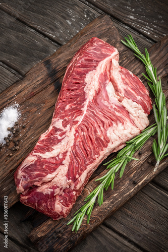 Raw hanging tender or onglet steak of beef on wooden Board with rosemary and pepper on wooden background photo