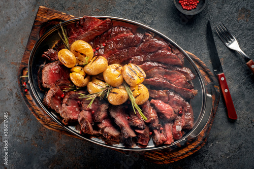 Hot Mix of grilled steaks on a plate with potatoes and rosemary, top view