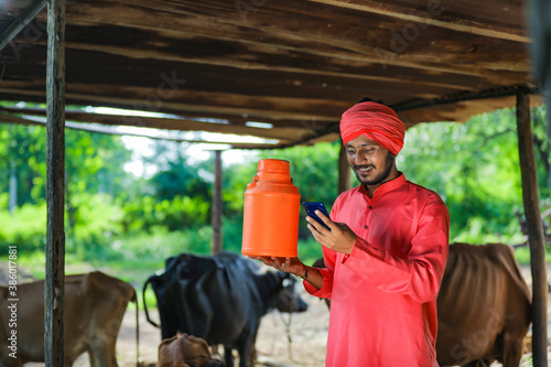 Indian farmer holding milk bottle in hand at dairy farm