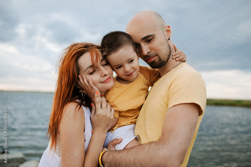 Happy family spends fun time by the lake. Parents with son have fun together