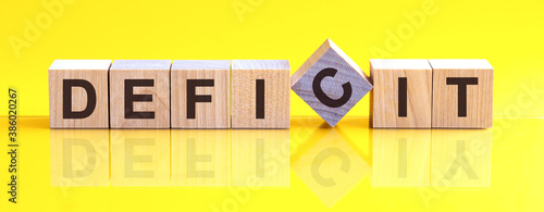 Fotografi deficit word is made of wooden building blocks lying on the yellow table