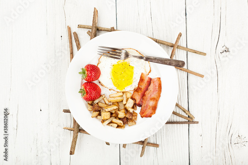 Bacon, eggs and potatoes breakfast on a rustic wood background photo