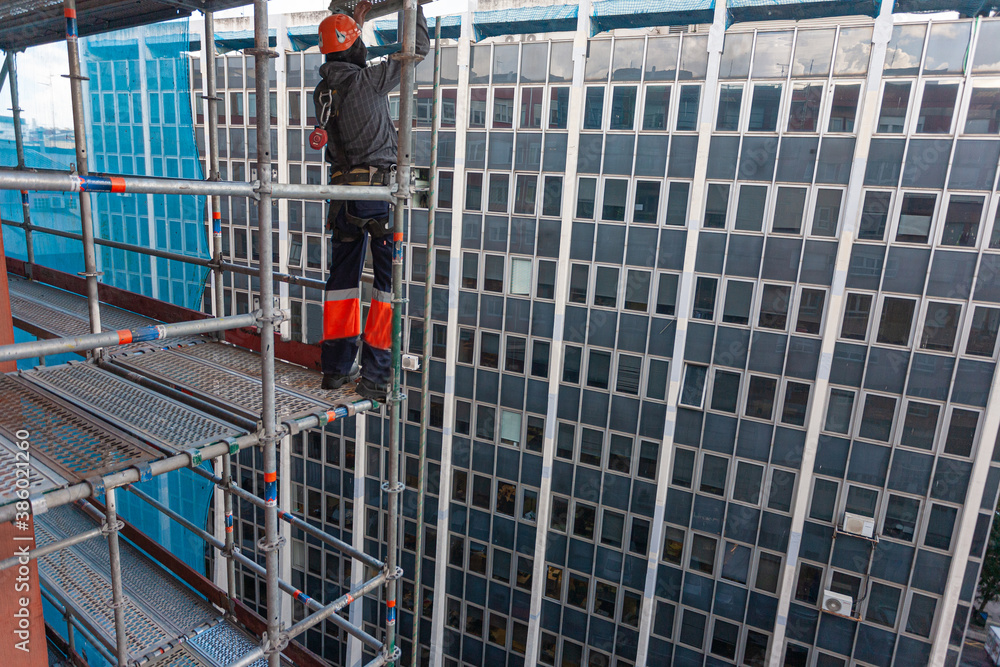 obrero de la construcción colocando un andamio de obra para reparar una fachada 