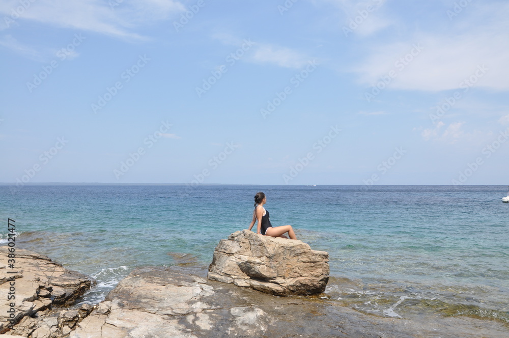 Teen age girl sitting on the rock. Relaxing on the beach. Adriatic Sea. Teen age girl sitting on the rock. Relaxing on the beach. Adriatic Sea.