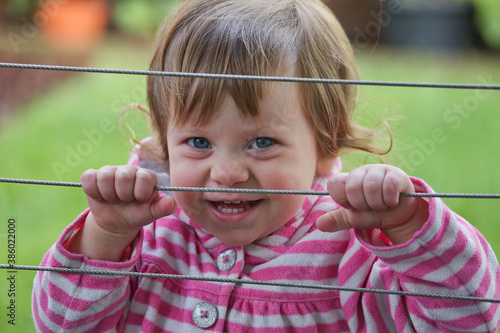 Close up Portrait of Cute 18 month Old Happy Toddler Girl with Big Blue Eyes and Curly Brown Hair. Adorable Baby Girl, Happy and Healthy Baby