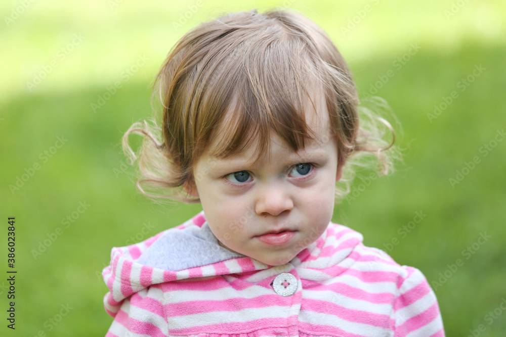 Close Up Portrait of a little 18 Month Old Girl with Big Blue Eyes and Curly Hair, a girl Playing Outside, Funny Face Expression, Happy baby Close Up Portrait of a little 18 Month Old Girl with Big Blue Eyes and Curly Hair, a girl Playing Outside, Funny Face Expression, Happy baby