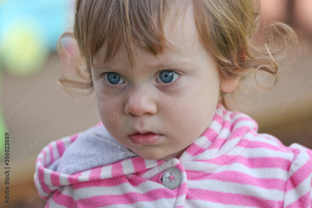 Close Up Portrait of a little 18 Month Old Girl with Big Blue Eyes and Curly Hair, a girl Playing Outside, Funny Face Expression, Happy baby Close Up Portrait of a little 18 Month Old Girl with Big Blue Eyes and Curly Hair, a girl Playing Outside, Funny Face Expression, Happy baby