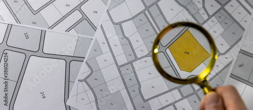 Billede på lærred hand with magnifier on cadastre map - search and buy land concept