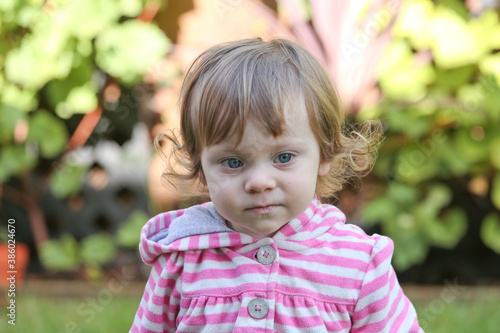 Close Up Portrait of a little 18 Month Old Girl with Big Blue Eyes and Curly Hair, a girl Playing Outside, Funny Face Expression, Happy baby