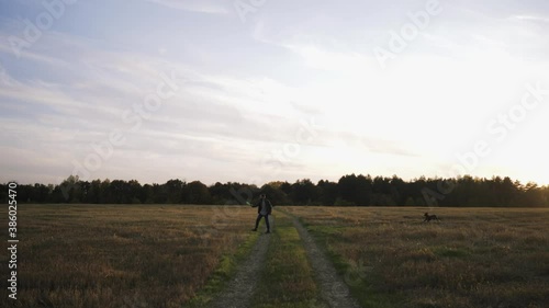 A young man walks in a field with his dog Kurzhaar and plays a flying saucer photo