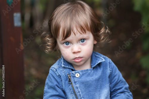 Close Up Portrait of a little 18 Month Old Girl with  Big Blue Eyes and Curly Hair  a girl Playing Outside  Funny Face Expression  Happy baby