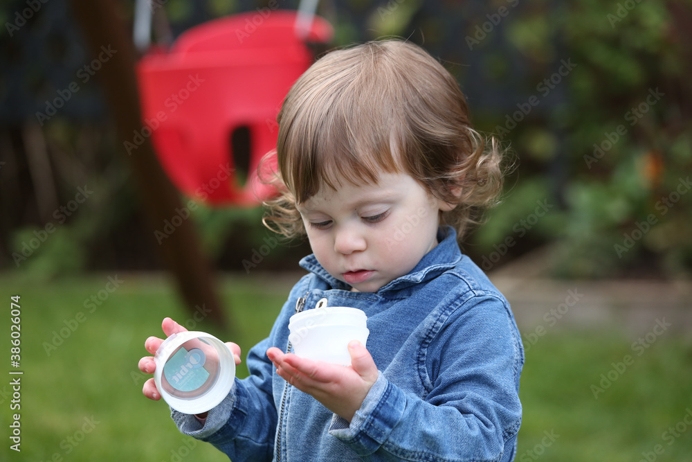 Close Up Portrait of a little 18 Month Old Girl with  Big Blue Eyes and Curly Hair, a girl Playing Outside, Funny Face Expression, Happy baby