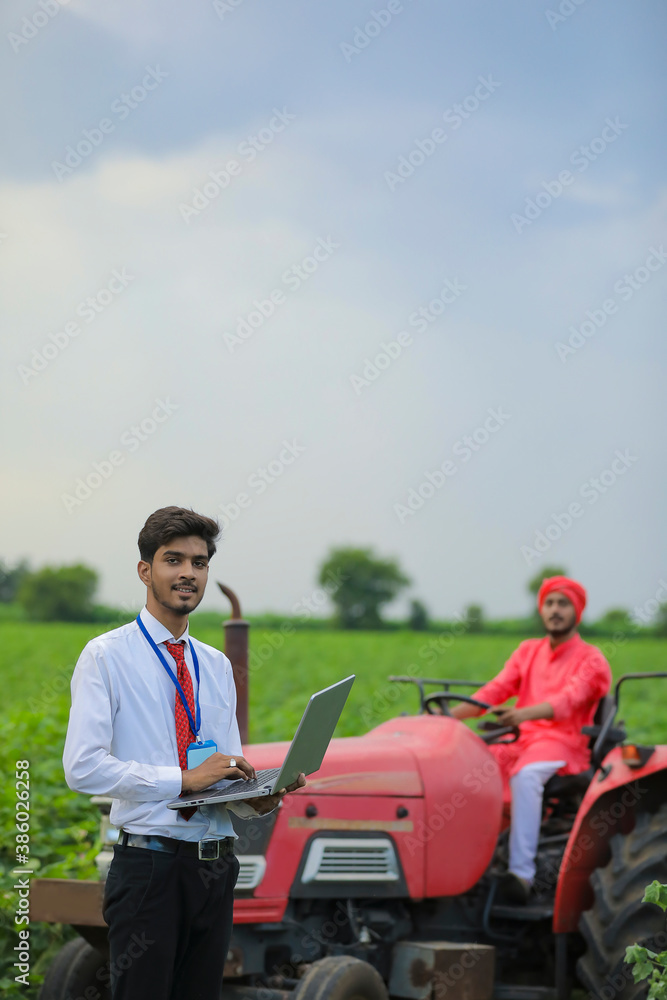 young Indian agronomist using laptop at field