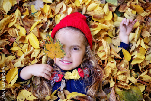 Cheerful child with yellow maple leafs having fun in autumn